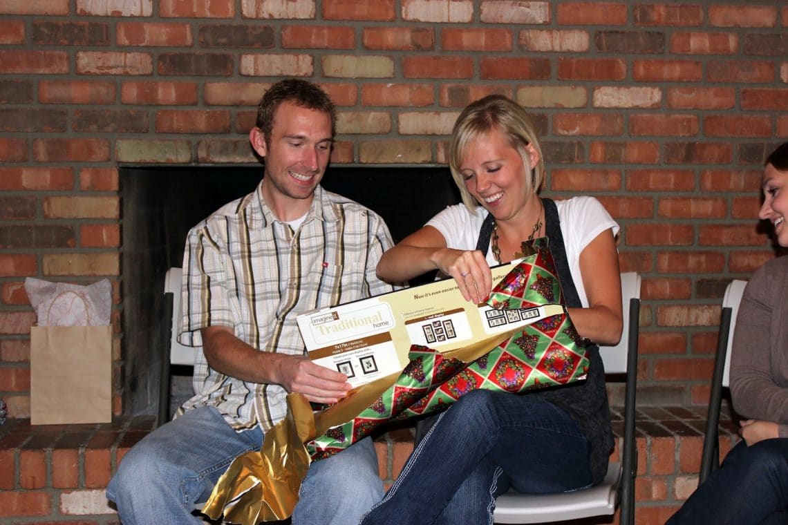 Couple unwrapping a white elephant party gift. 