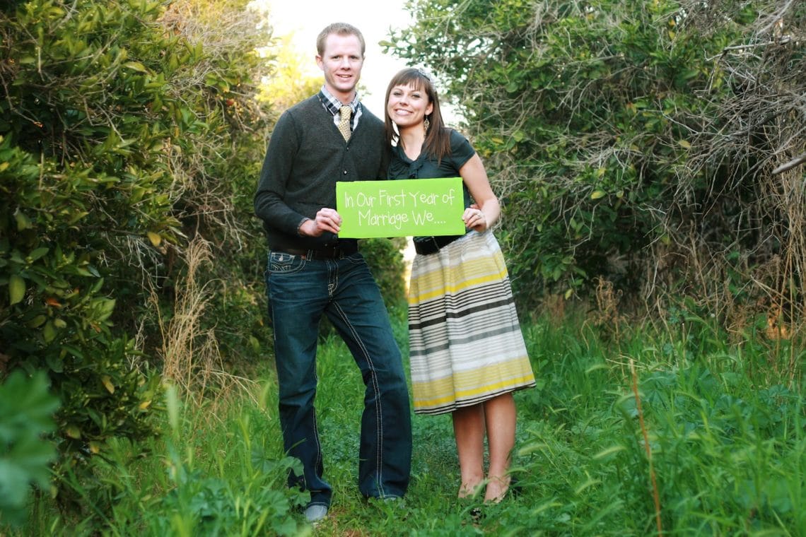 A married couple on their wedding anniversary holding signs that share the Highlights of the first year of marriage. 