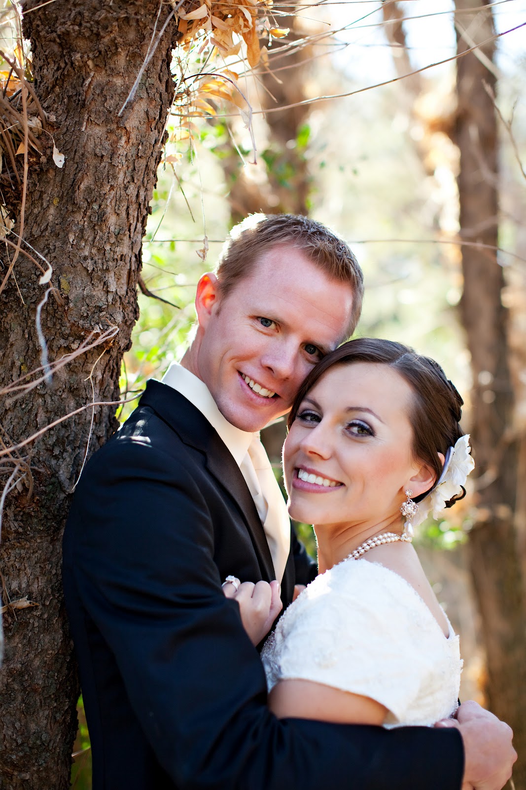 Couple snuggling up to each other smiling on their wedding day. 