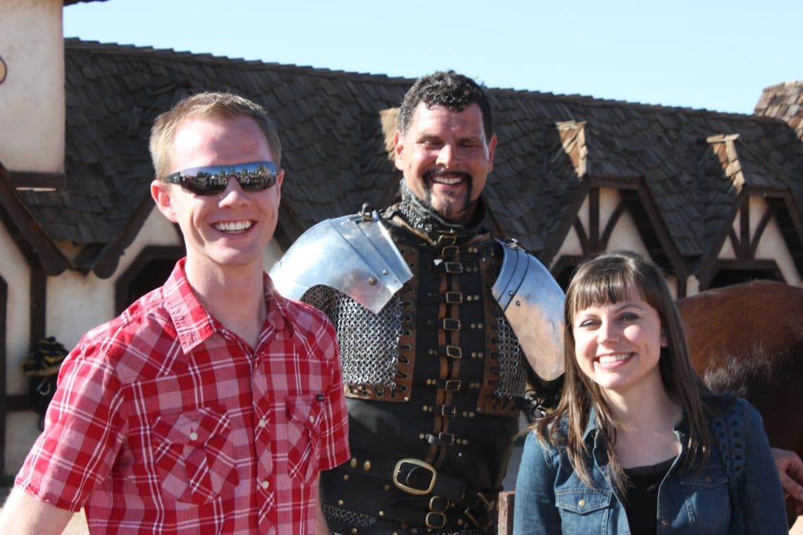 A couple on a date to the Arizona Renaissance Festival taking a picture with a knight after the jousting match. 