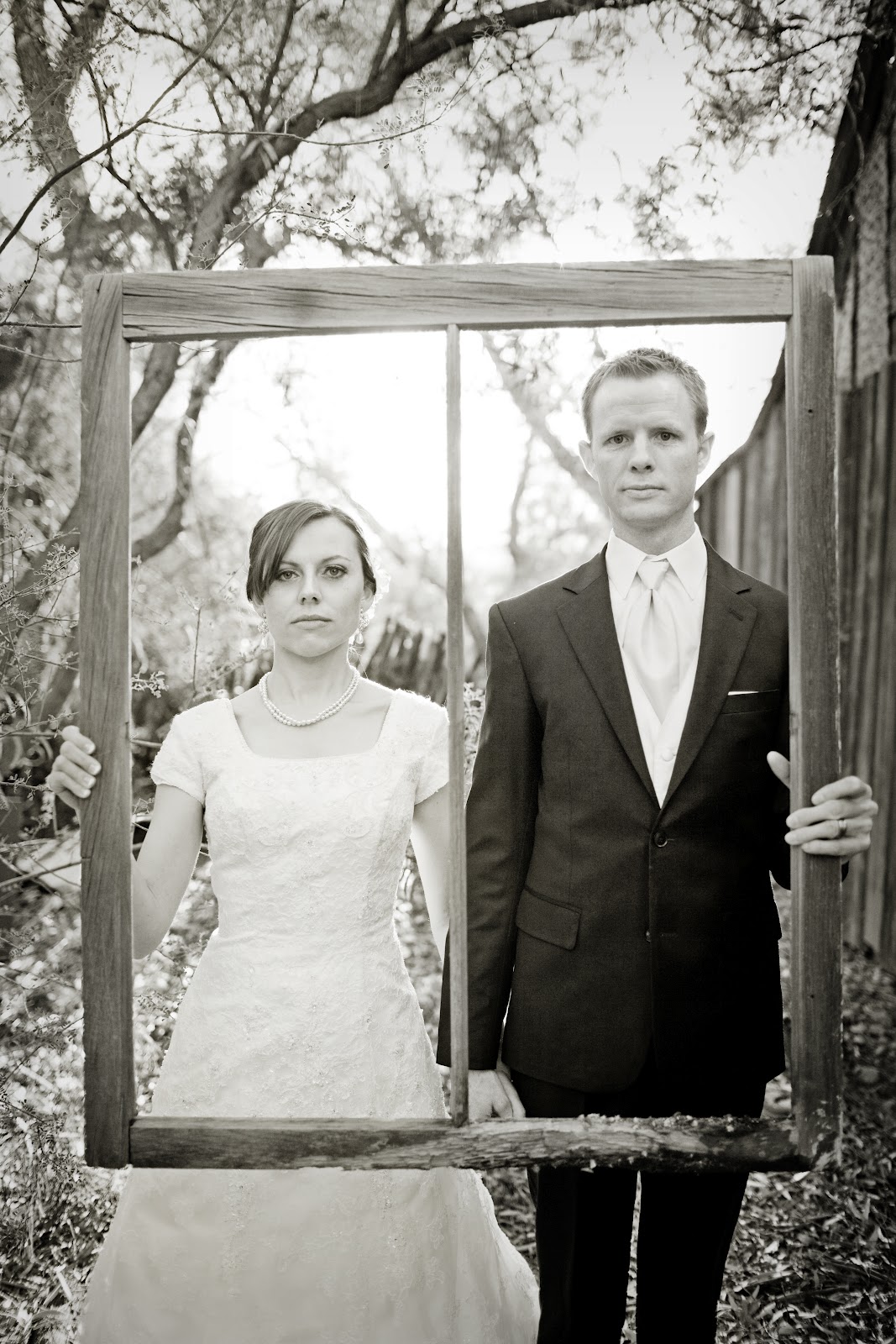 Funny wedding photo idea with the bride and groom holding a frame posing like the famous painting The Farmer\'s Wife. 