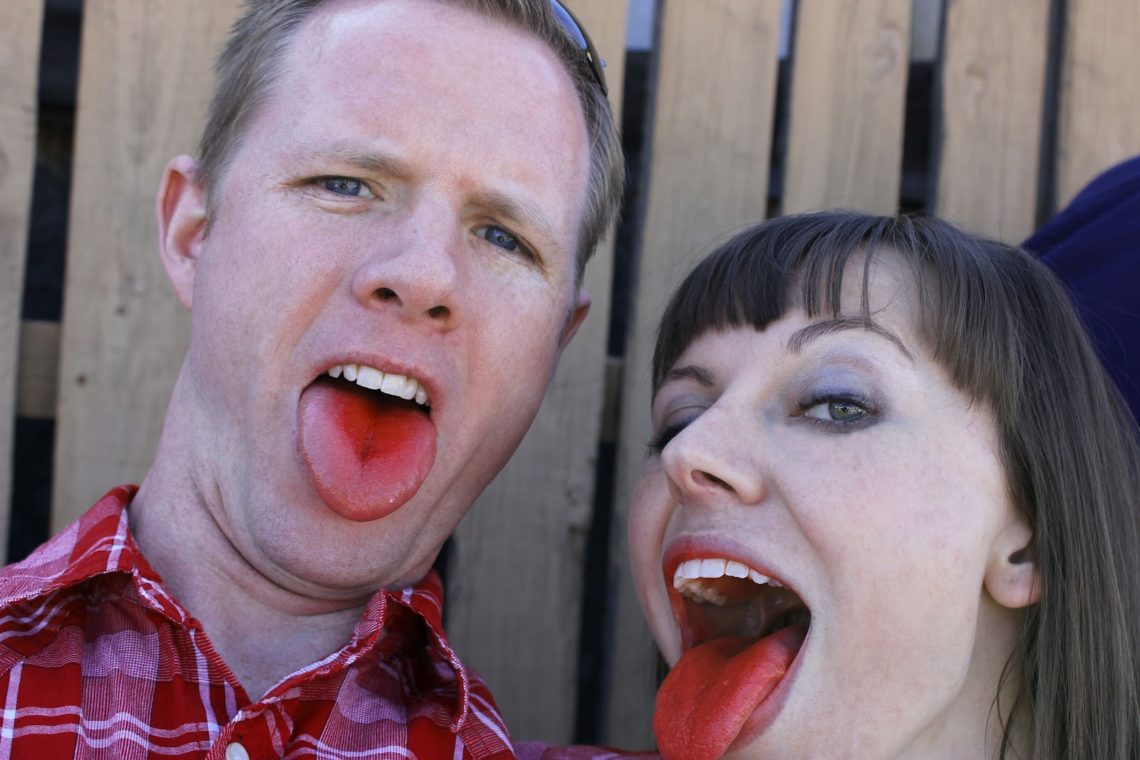 Couple showing their red tongues after eating a treat. 