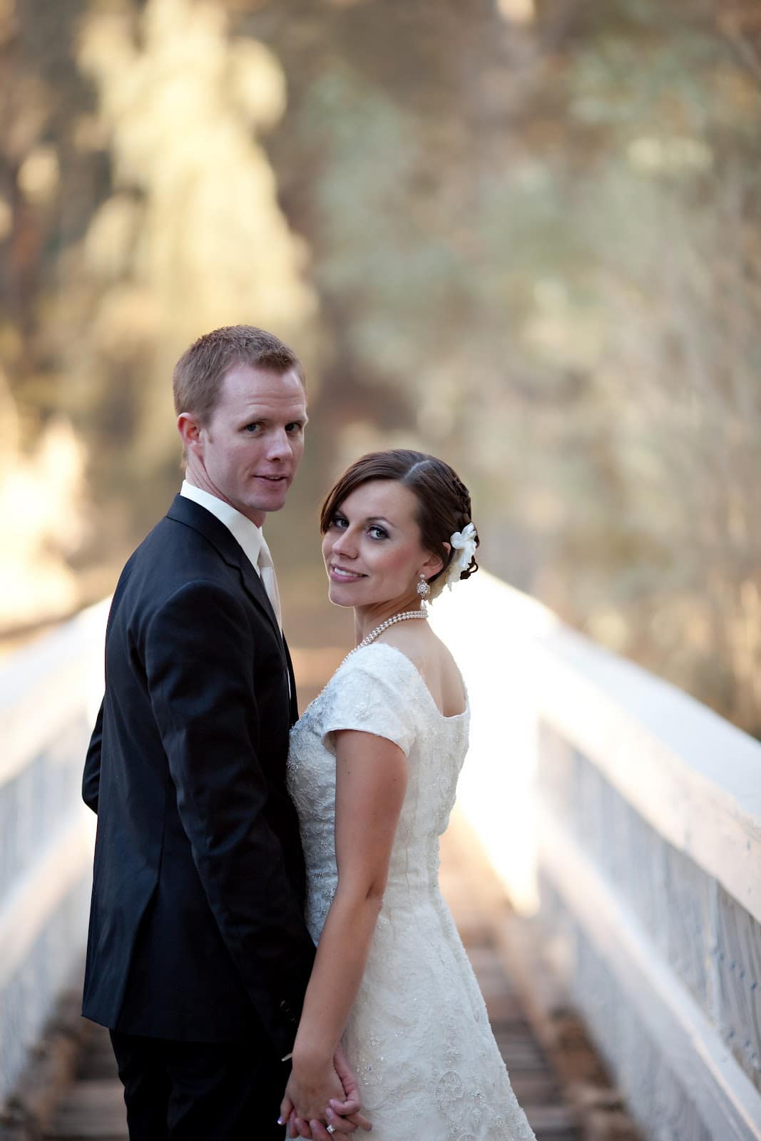 Bridal pictures with the bride and groom posing on a bridge.