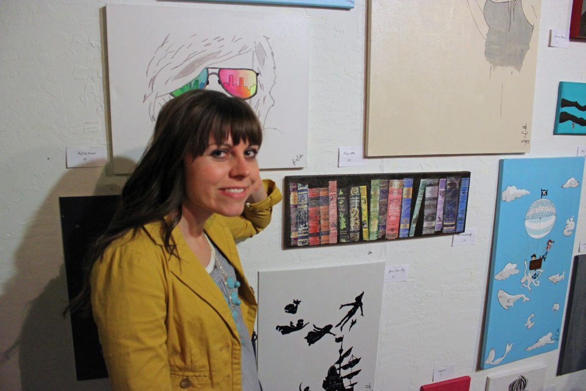 Woman in front of Art displays on First Friday. 