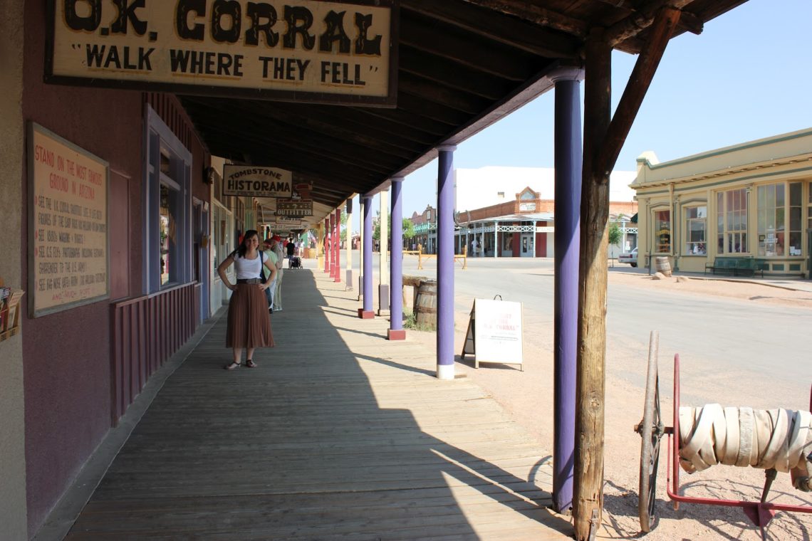 Woman posing in front of a Sign for the O.K. Corral Gunfight site in Tombstone Arizona. 