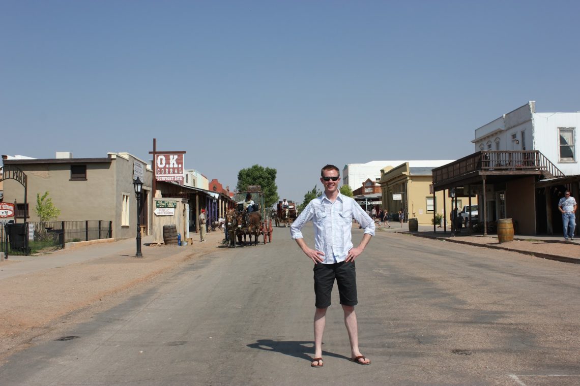 A man standing in front of the historic town of Tombstone Arizona. 