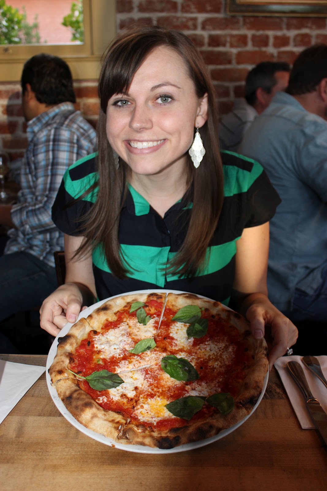 Woman showing a pizza on a Pizzeria Bianco Date Night. 