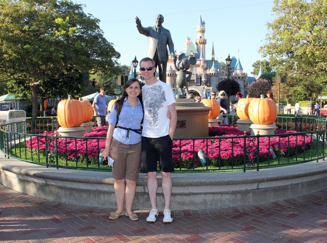 Disneyland date: couple in front of Walt Disney statue. 