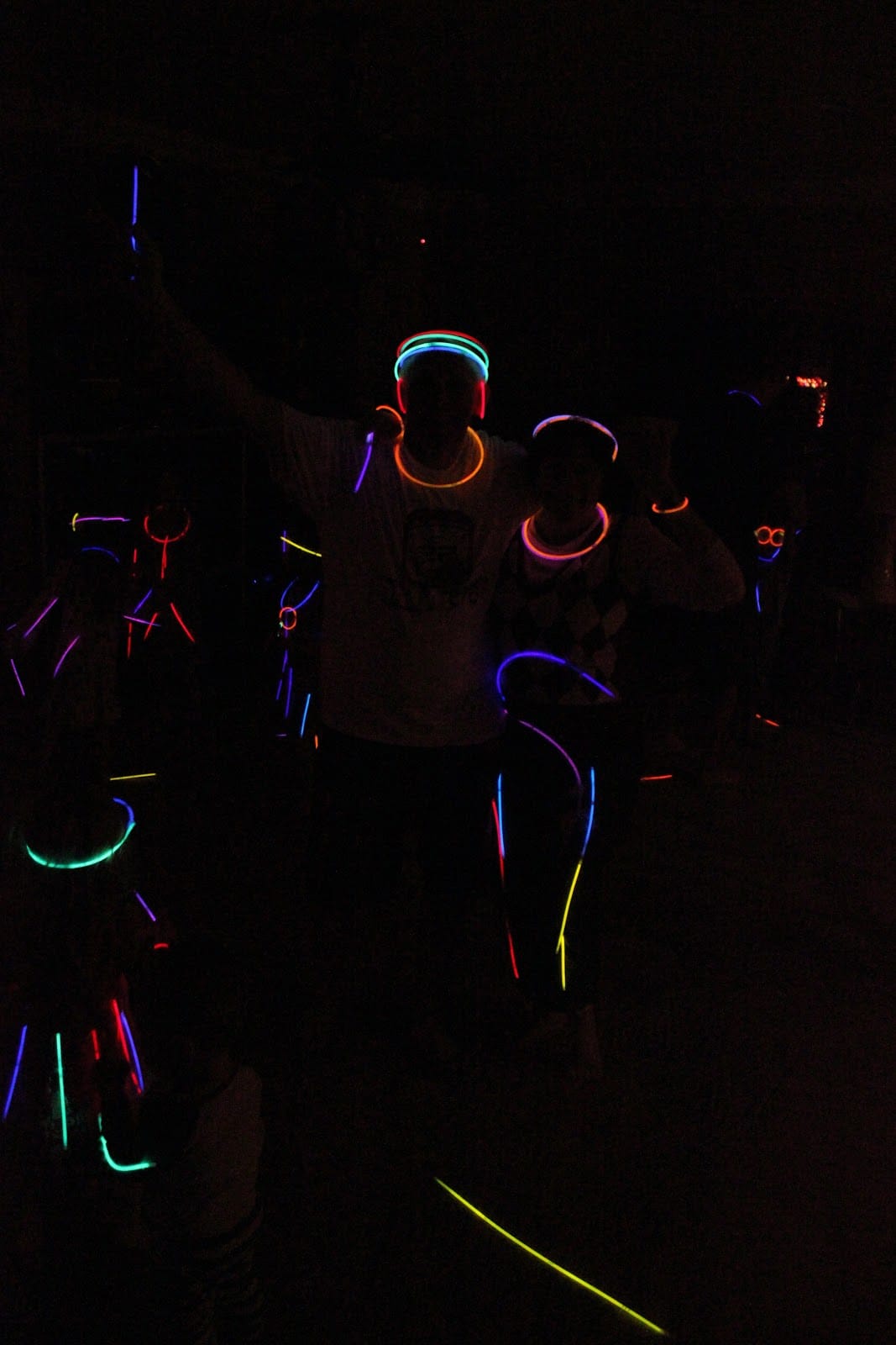 A family dance party with glow sticks during a blacklight dance party for kids. 