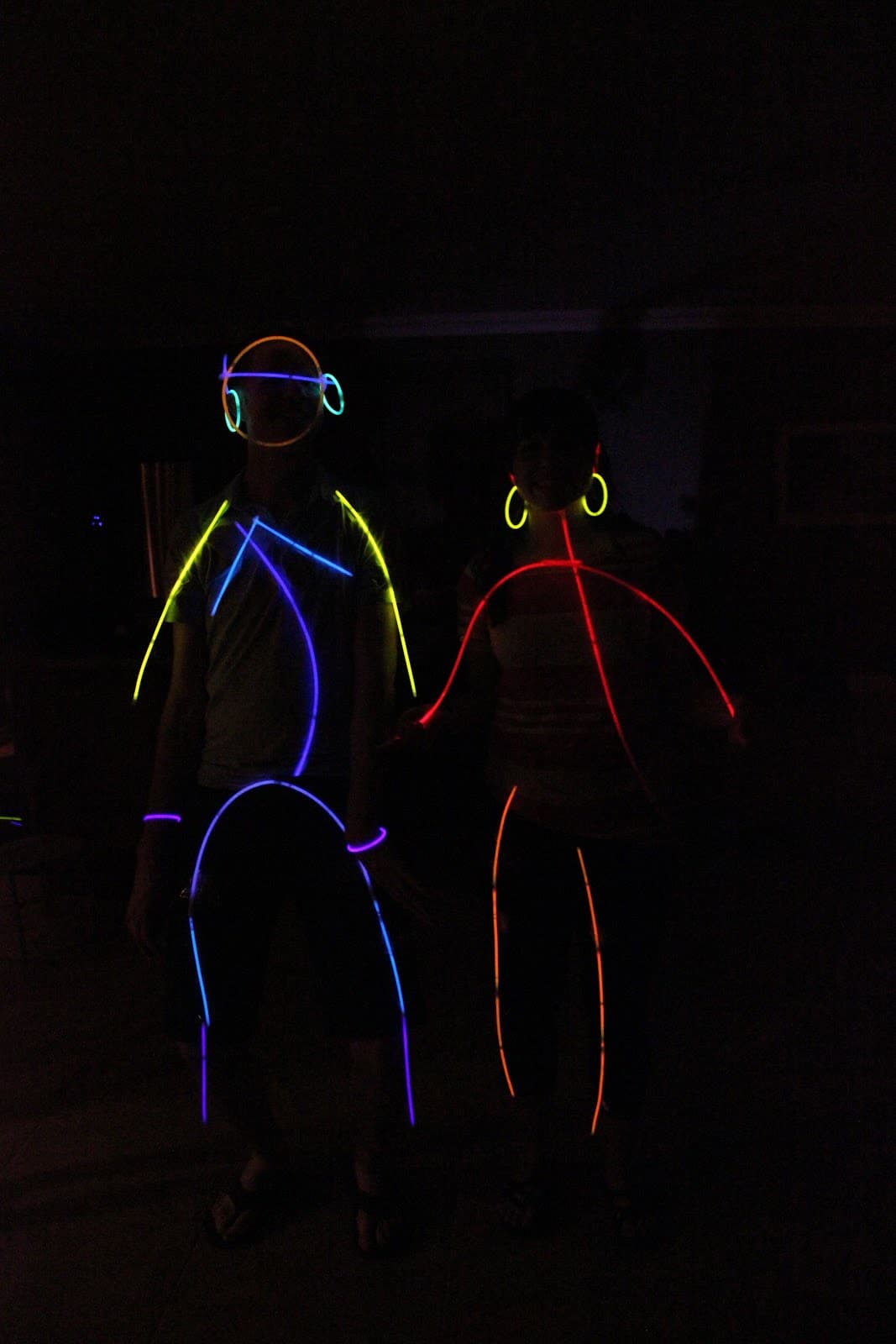 A couple dressed as stick figured with glow sticks during a glow stick dance party. 