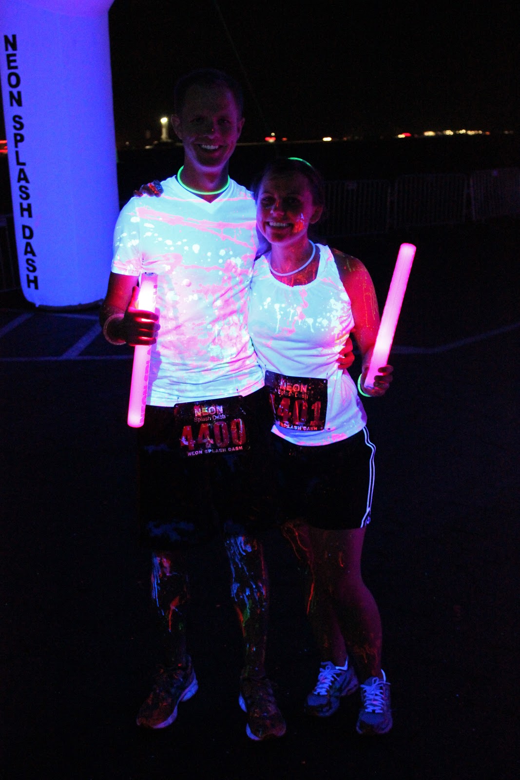 A couple pausing for a photo during The Neon Splash and Dash 5k. 