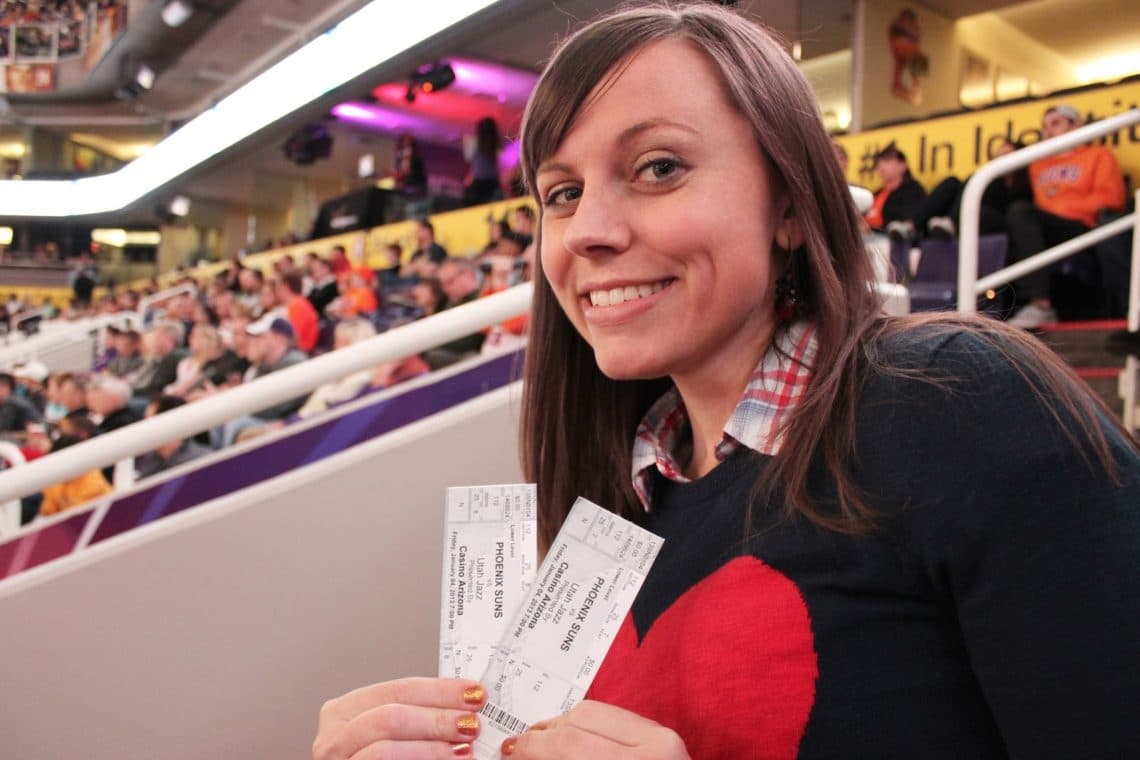 Woman holding two tickets for an NBA basketball game date night. 