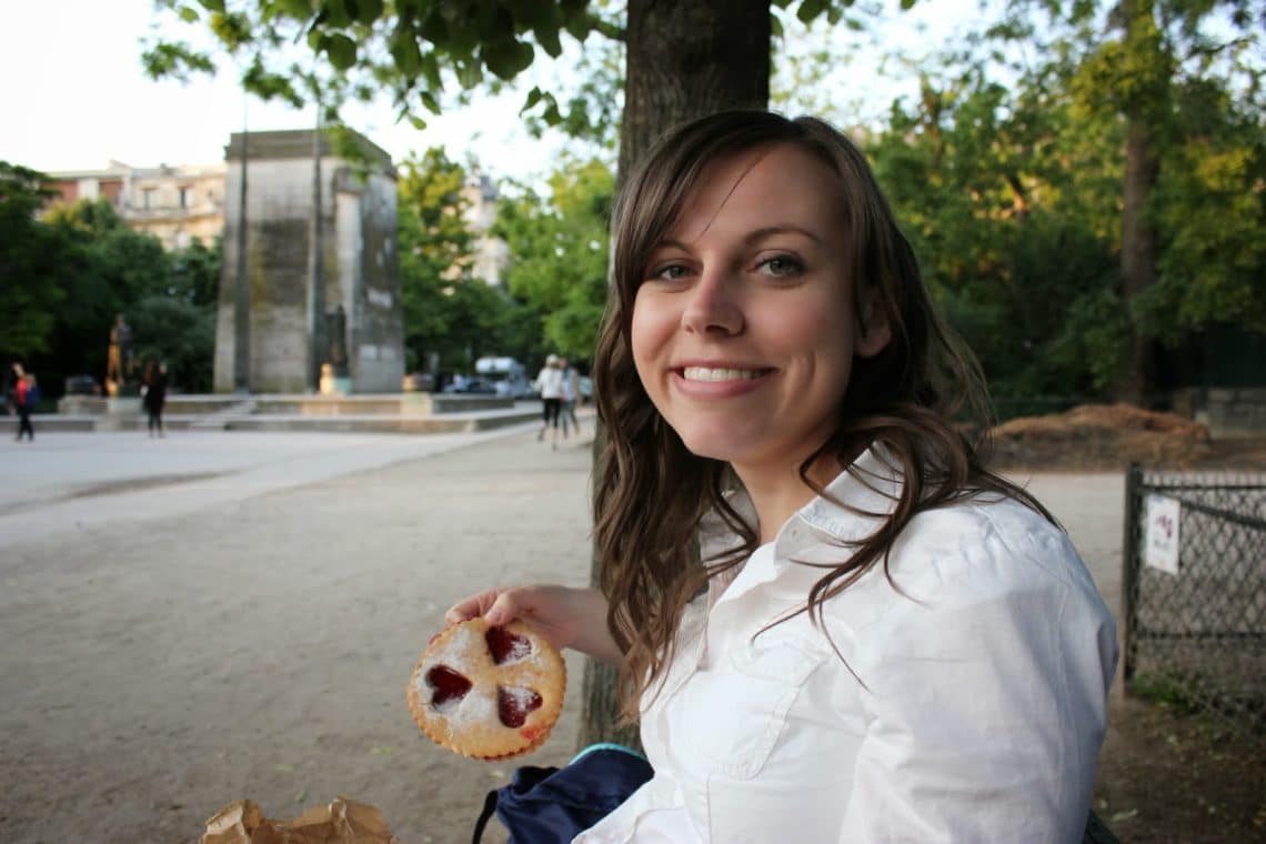 Women holding pastry on a park bench for a Picnic by the Eiffel Tower. 