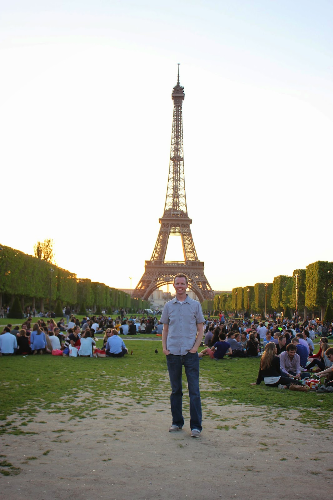 Man standing in front of The sun setting behind the The Eiffel Tower. 