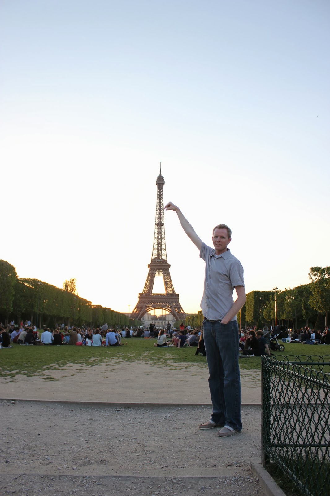 Tourist picture in front of The sun setting behind the The Eiffel Tower. 
