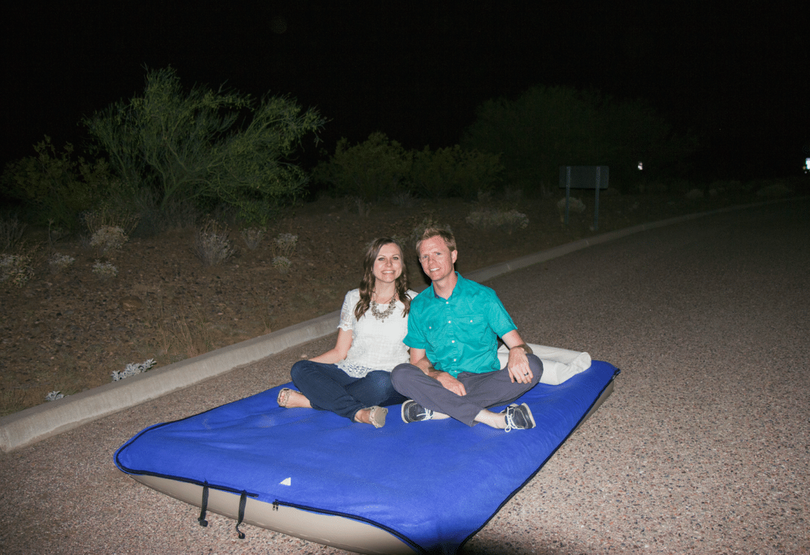Couple sitting on an air mattress enjoying a stargazing date night. 