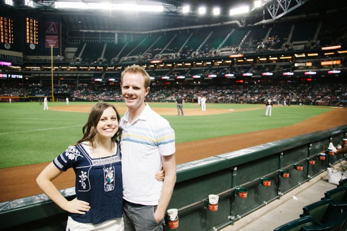 A couple in front of the field for a Baseball date night. 