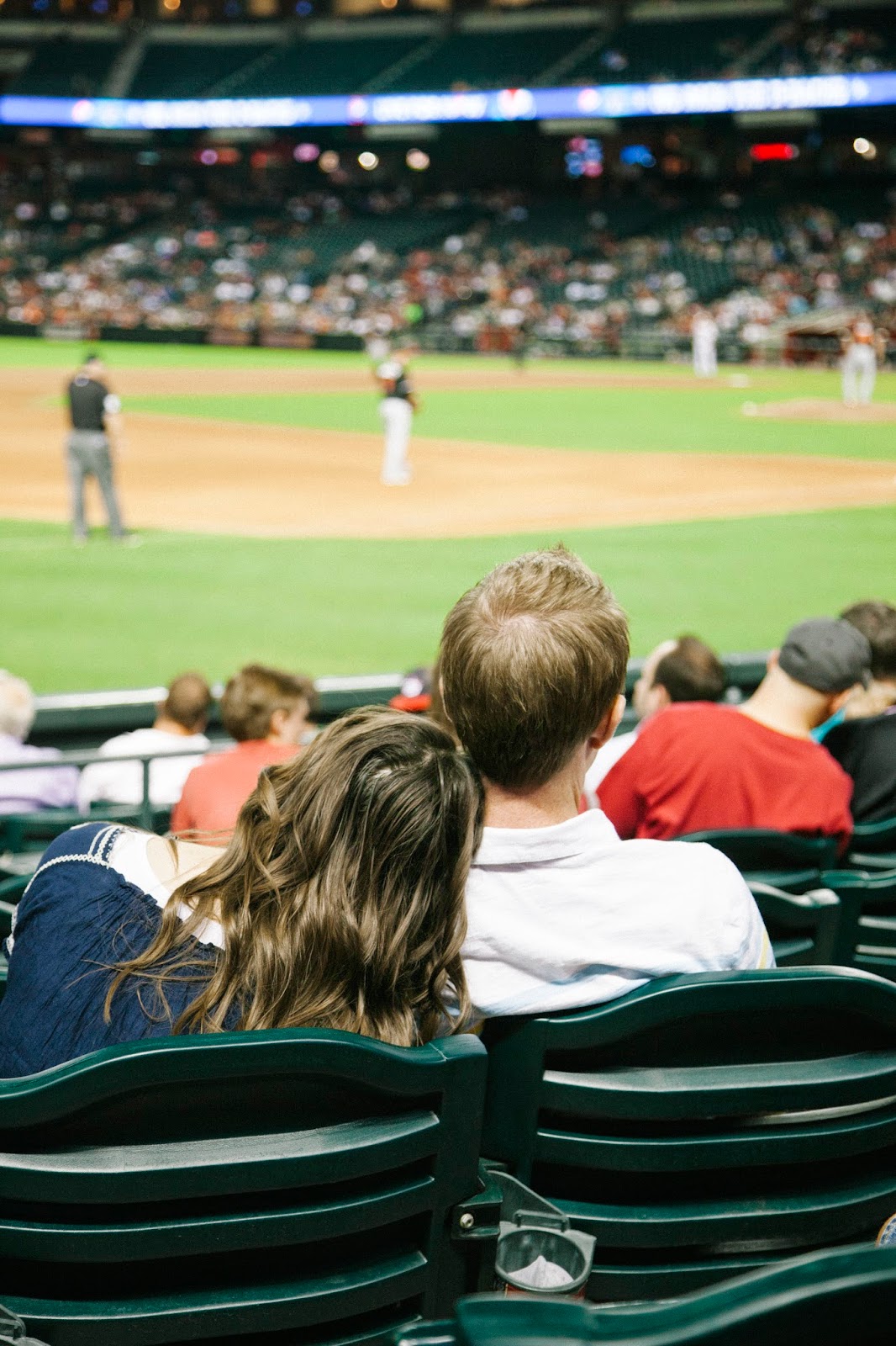 A couple watching the game and cuddling up during a Baseball date night. 