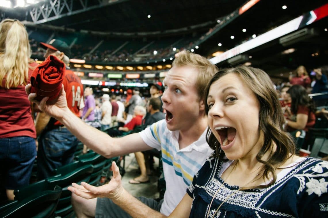 A couple enjoying trying to catch free shirts during a Baseball date night. 