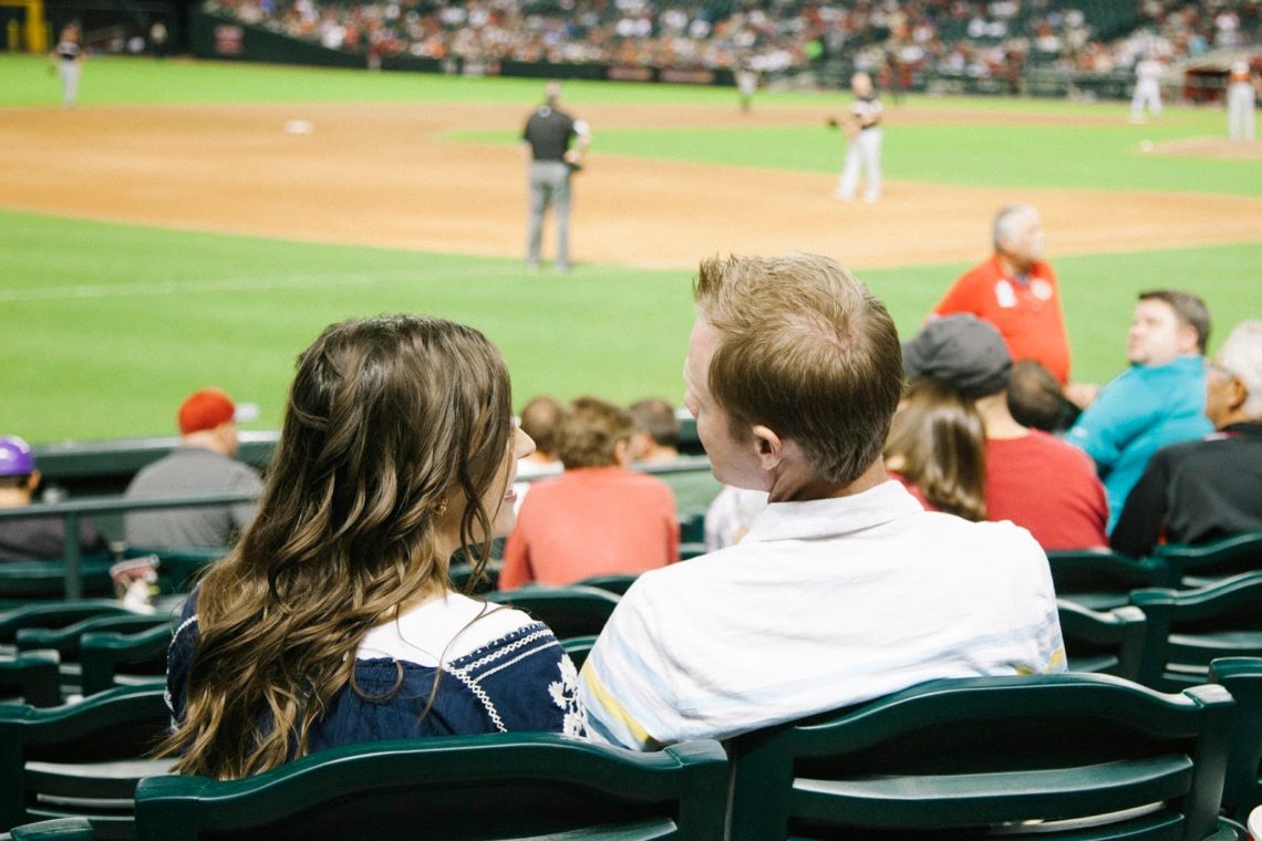 A couple from behind watching a game for a Baseball date night. 
