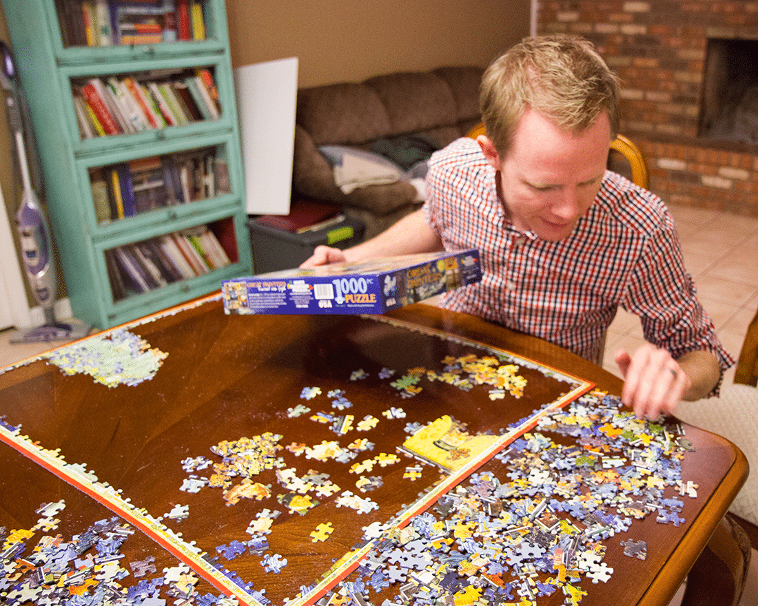 A husband doing a jigsaw puzzle for a puzzle date night at home. 