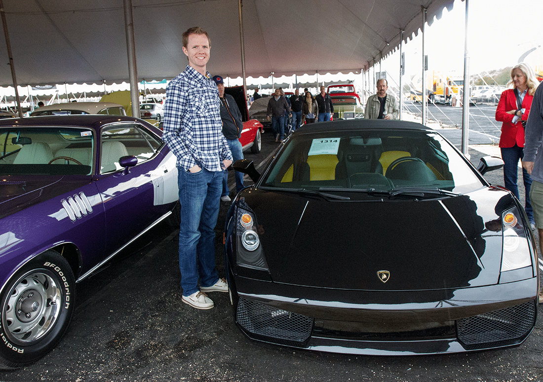 Man in front of black car at Barrett Jackson auto show. 