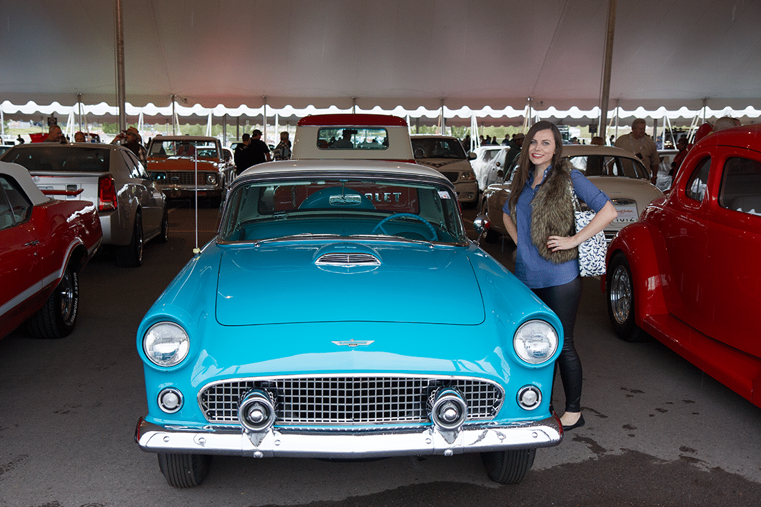 Woman next to vintage car at Barrett Jackson auto show. 