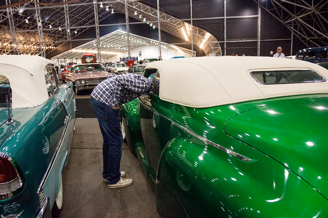 Man checking out a restored car at Barrett Jackson auto show. 