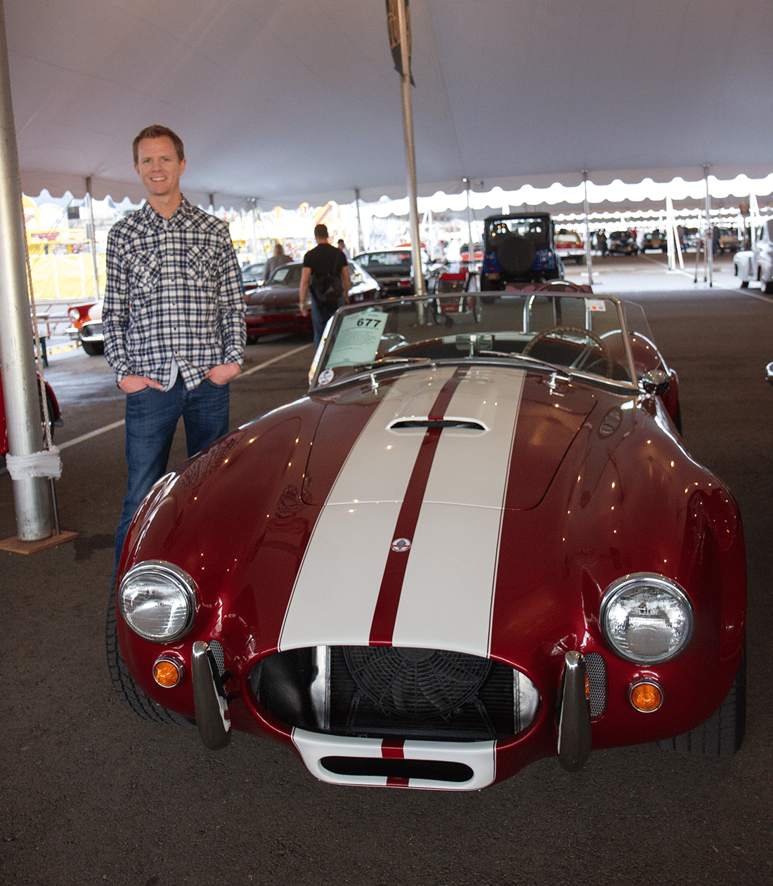 Man in front of vintage car at Barrett Jackson auto show. 