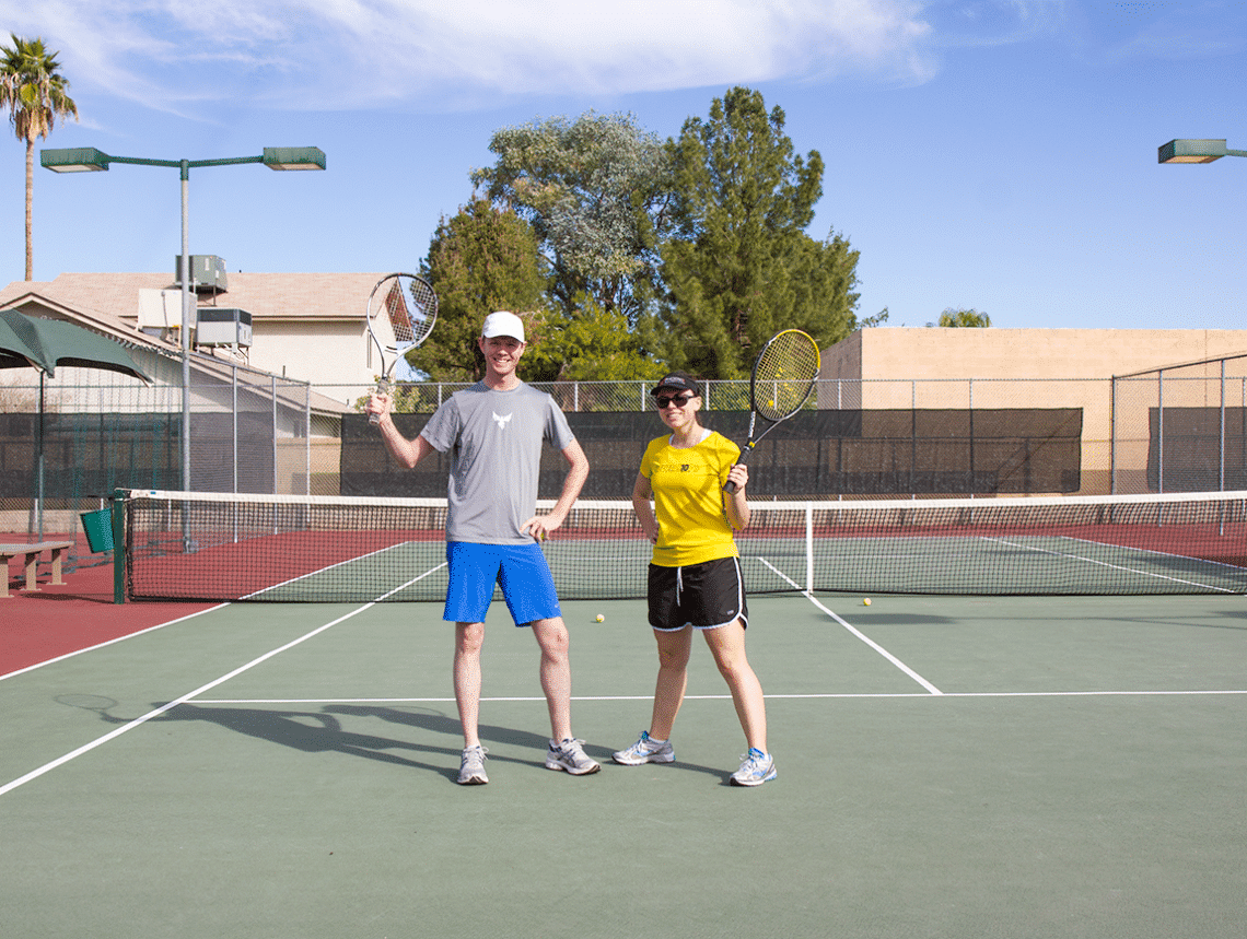 Couple about to play tennis on a tennis court. 