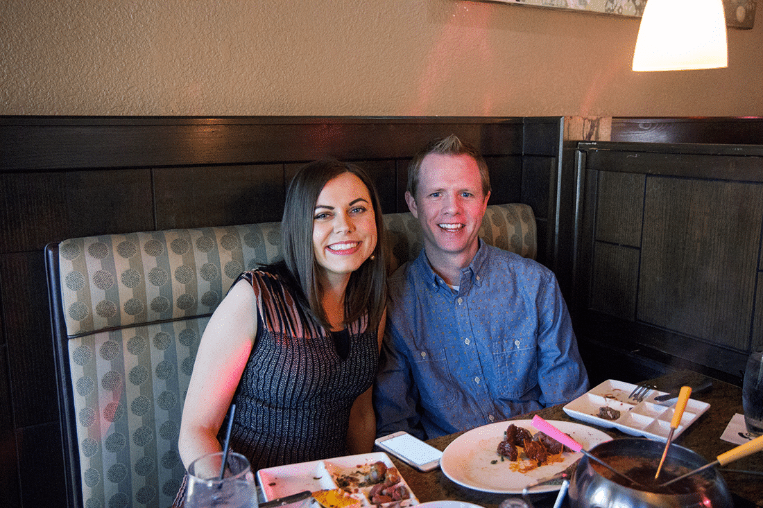 Couple sitting by each other holding fondue sticks at the Melting Pot. 