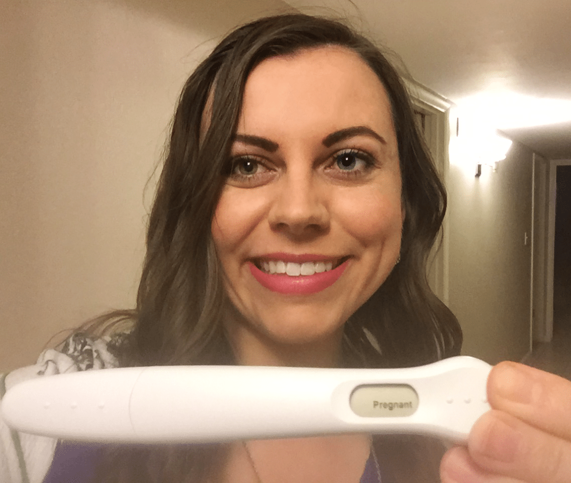 A women holding a positive pregnancy test after years of infertility. 