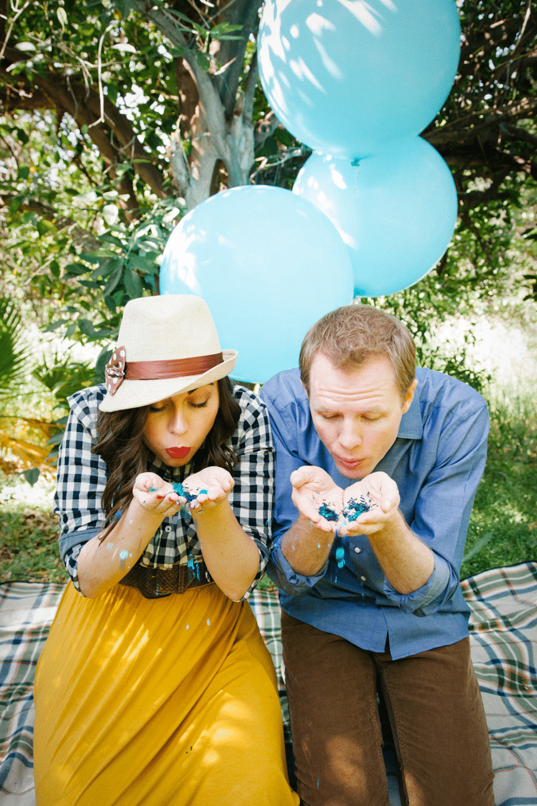 Couple blowing confetti at the camera for a gender reveal picture. 