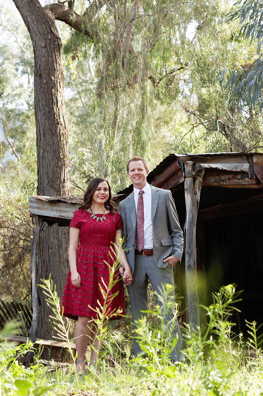 Cute couple anniversary pictures with a wife in a red dress and husband in a gray suit. 