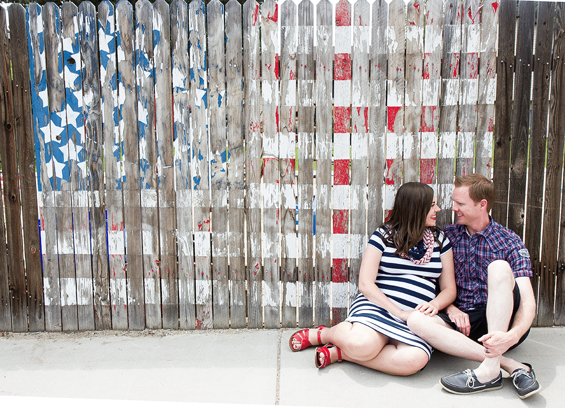 Couple in front of an American flag painted fence enjoying a 4th of July date. 
