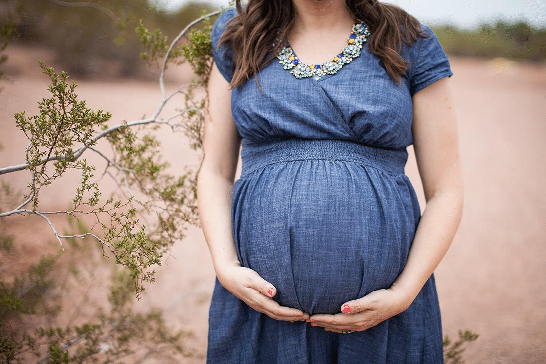 Expecting Mom holding baby bump during maternity pictures at Papago Park. 