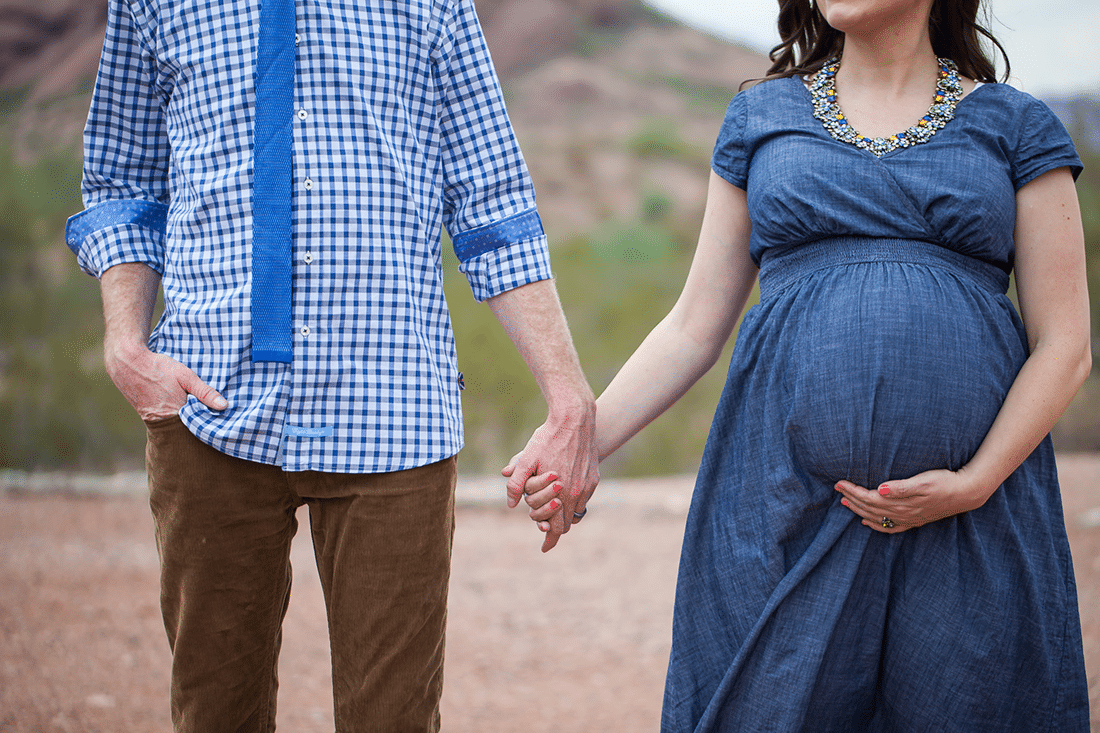 Husband and wife holding hands in maternity photo shoot. 