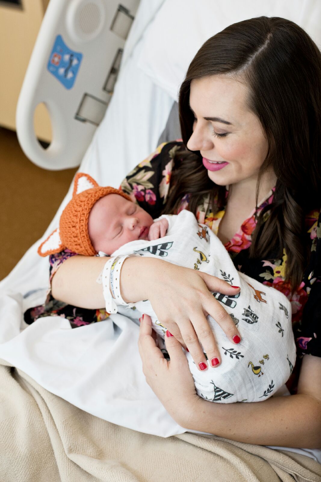 Mom holding a baby in a swaddle in a hospital bed after giving birth. 