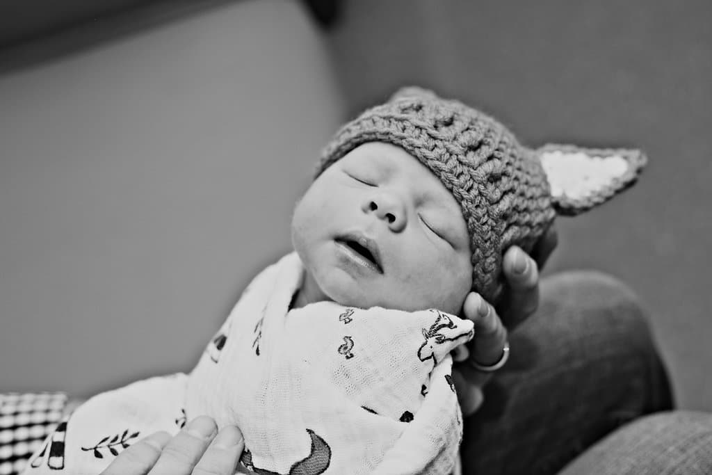 Precious Newborn Hospital Photo Session with parent holding new baby in their forearm. 