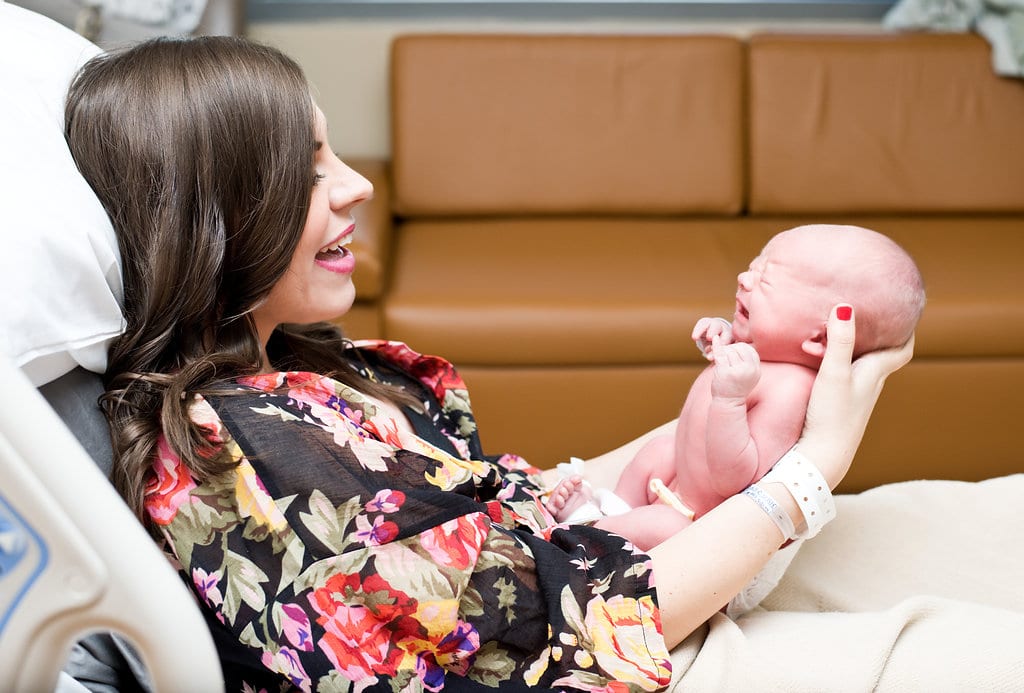 Mom holding brand new baby during newborn photography session. 