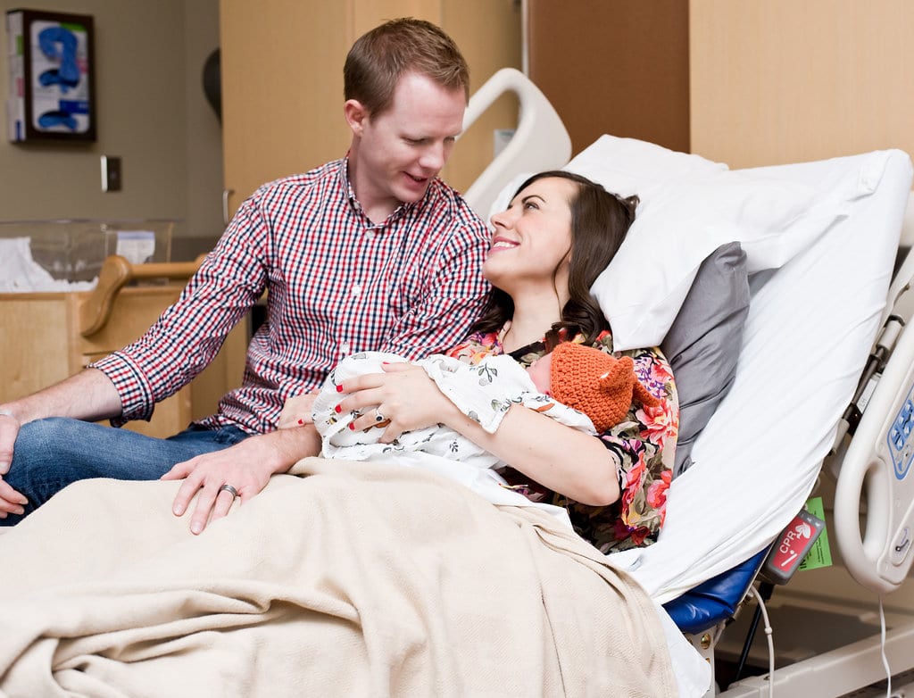 Birth Story Photography, couple looking at each other holding a newborn baby. 