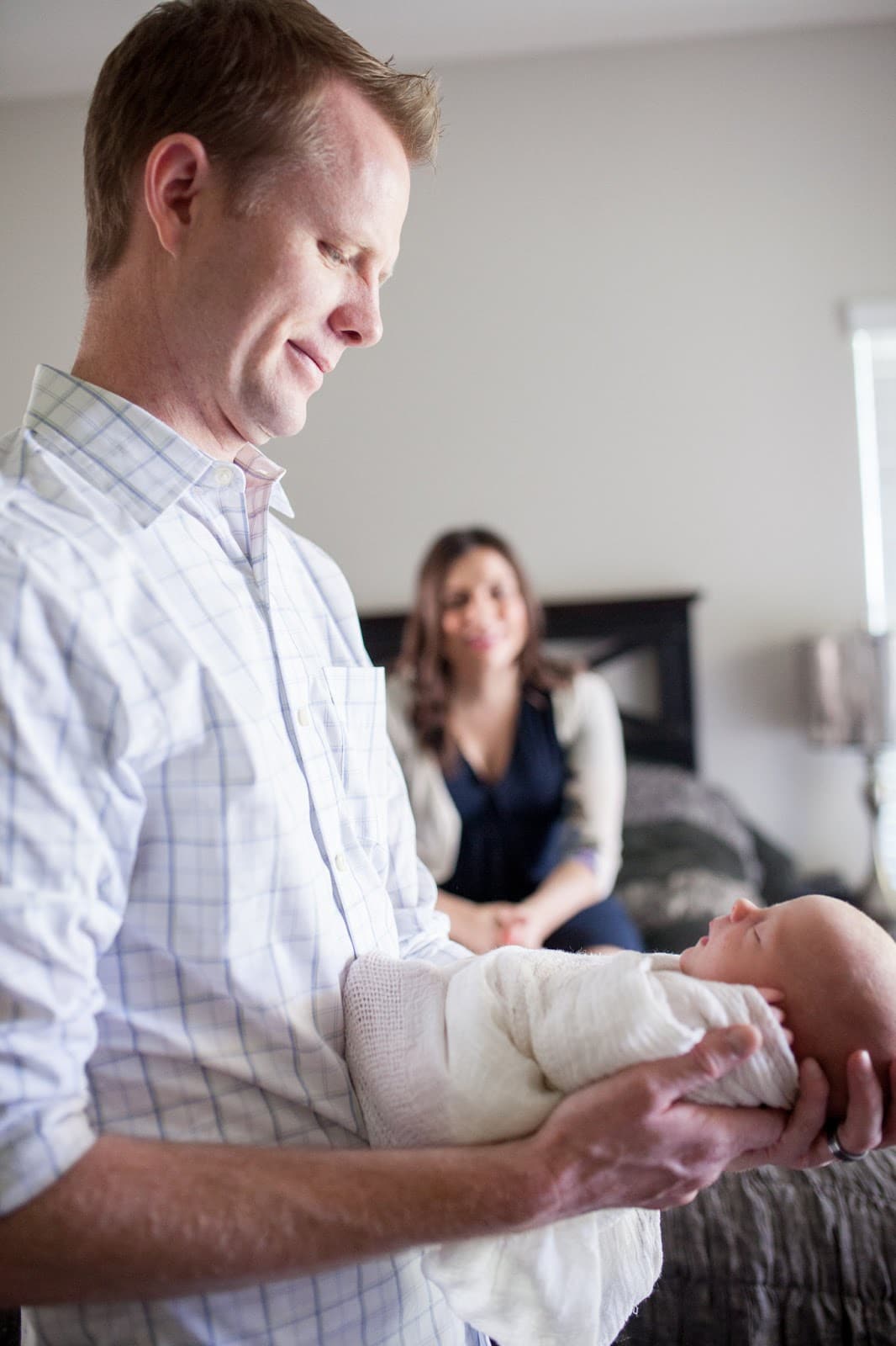 New dad holding a newborn baby looking with a smile. 