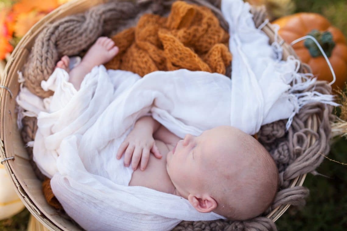 Baby in white swaddle taking newborn baby pictures. 