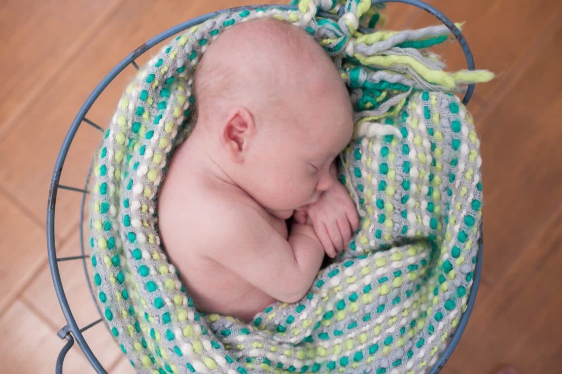 Newborn photography with baby asleep in a colorful blanket. 