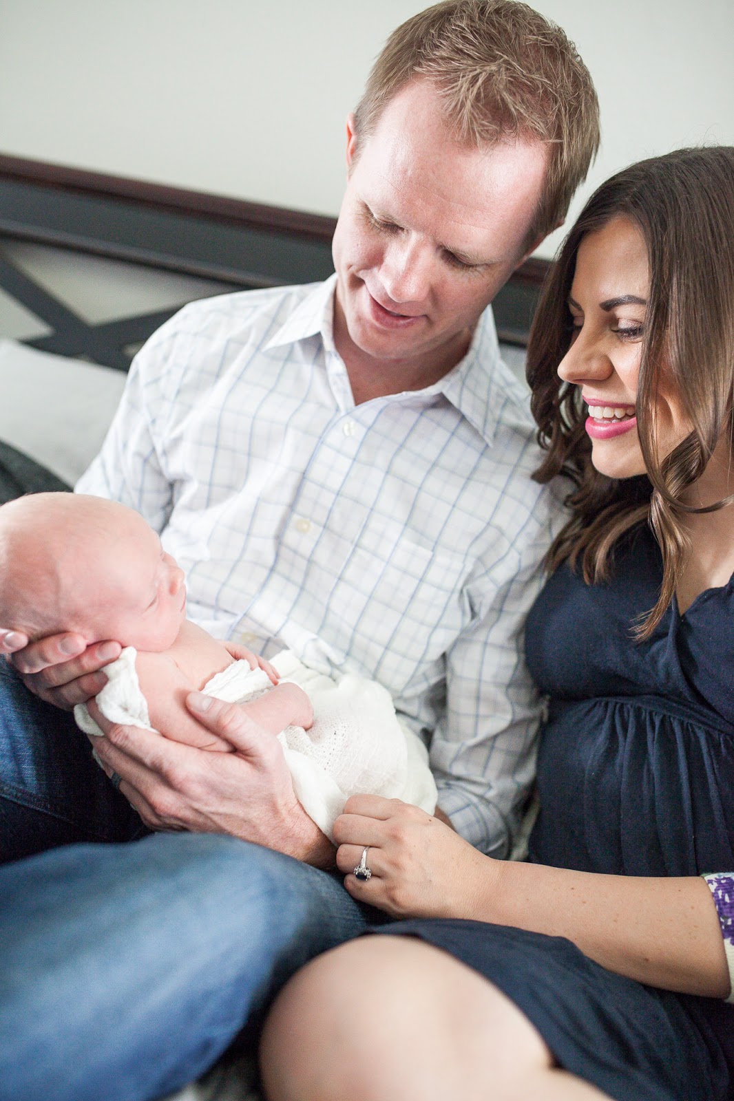 New parents smiling at newborn baby during a newborn photo shoot at home. 