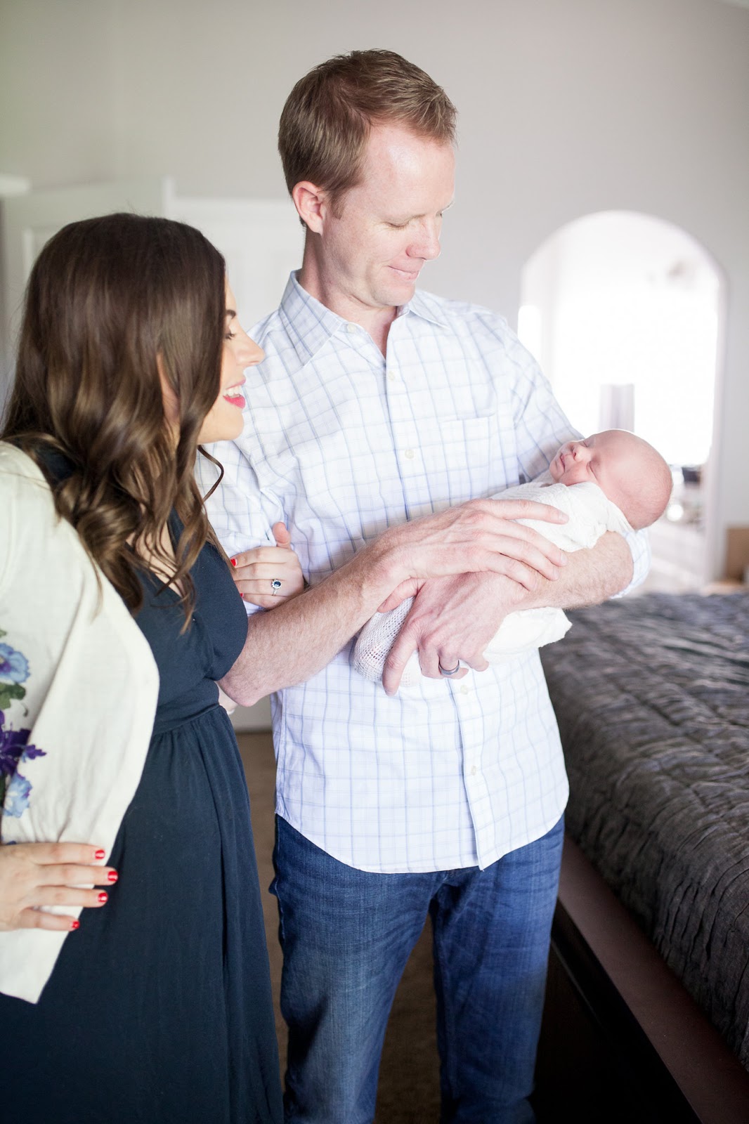 New mom and dad holding newborn baby and smiling. 