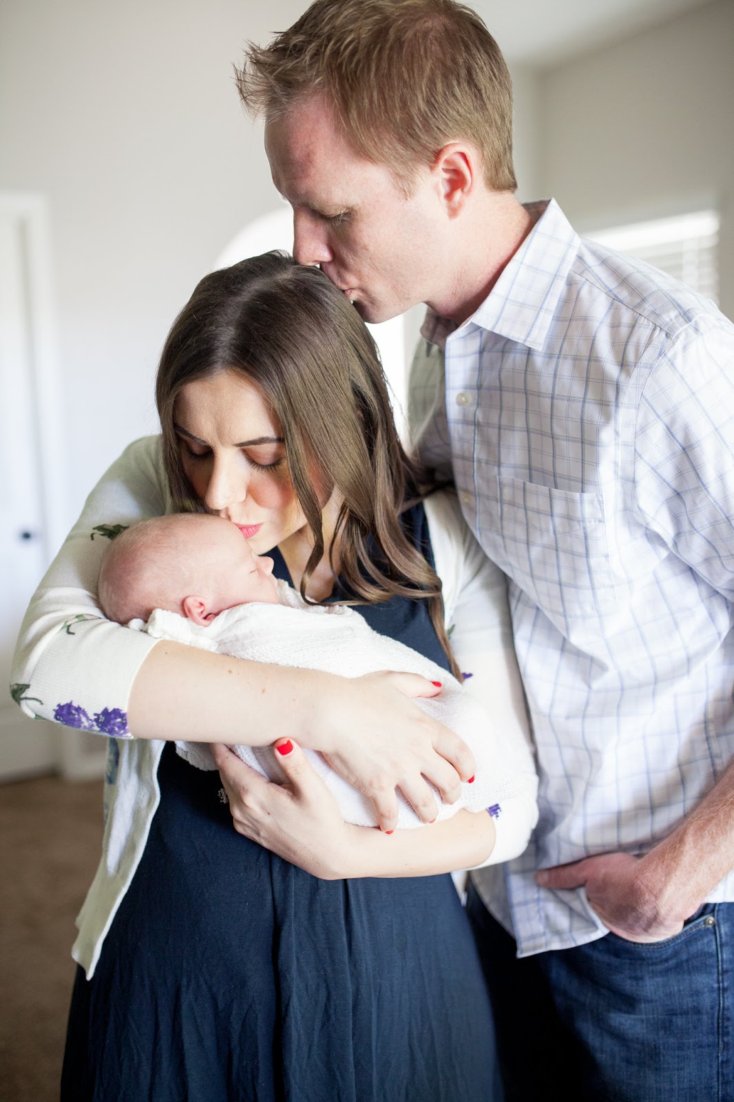 Newborn baby family pictures: mom and dad kissing newborn baby. 
