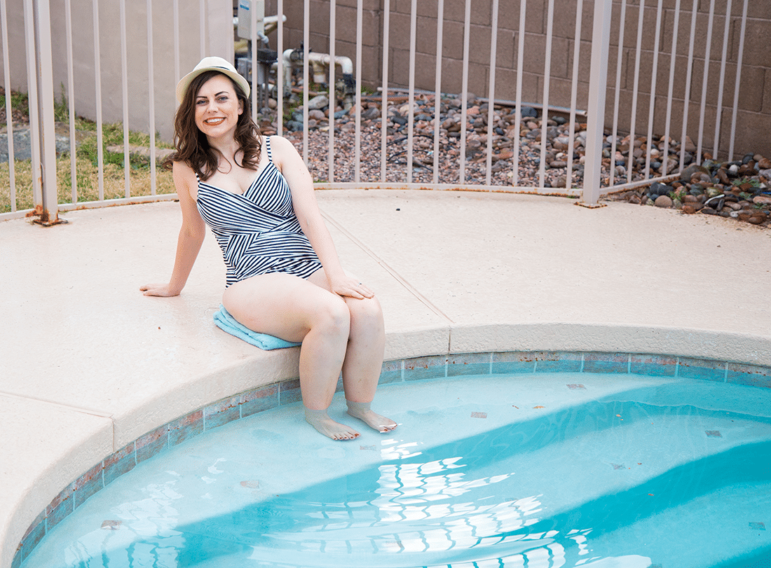 New Mom sitting next to the swimming pool in a bathing suit. 