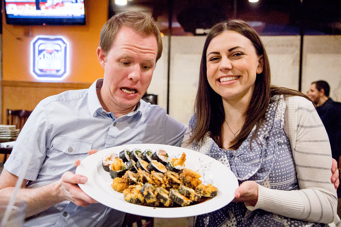 Couple holding a plate full of sushi on a sushi date. 