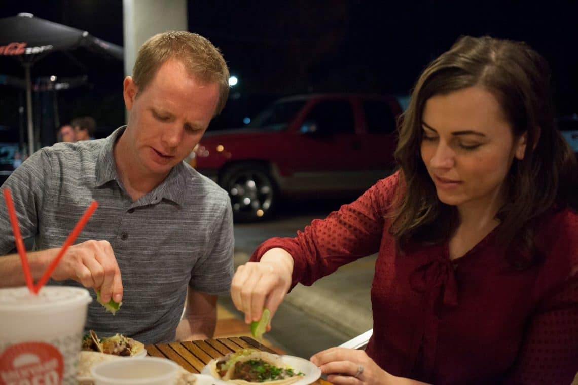 Couple getting ready to eat tacos squeezing limes on top. 